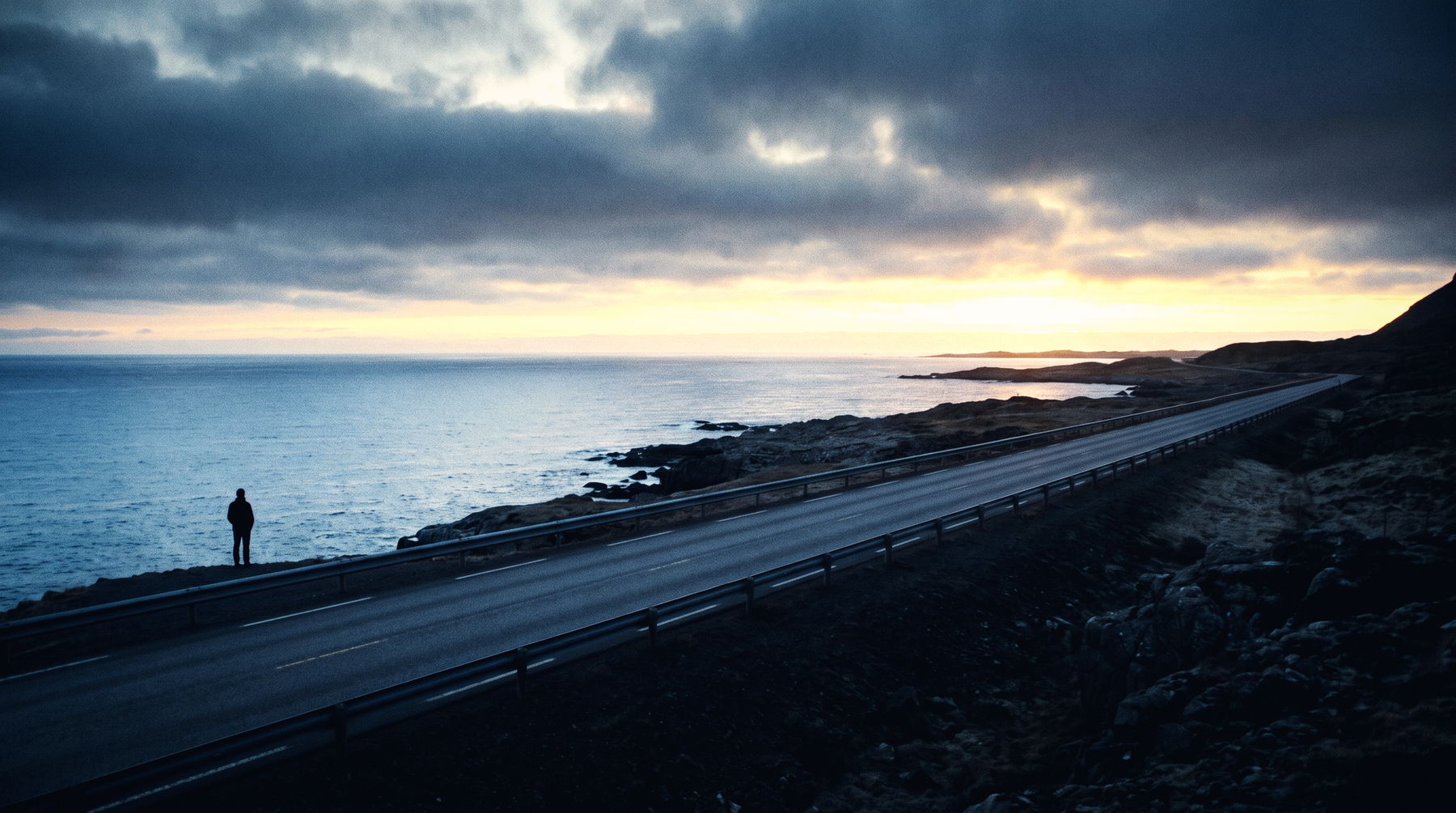 A lone figure on a coastal road at sunrise